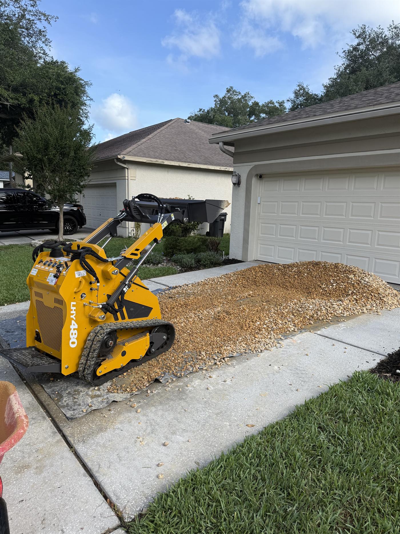 Compact tracked machine placing decorative rock during installation.