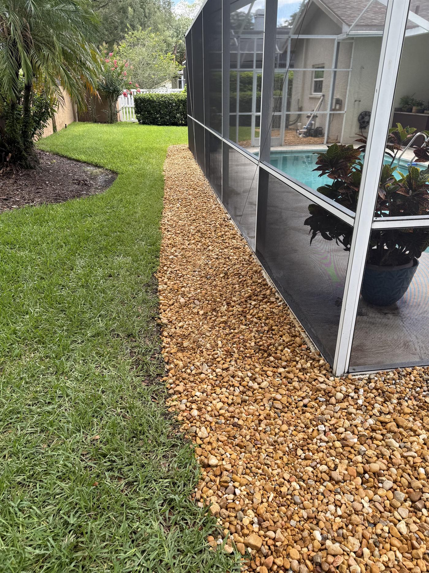 Finished decorative rock installation beside a screened enclosure.