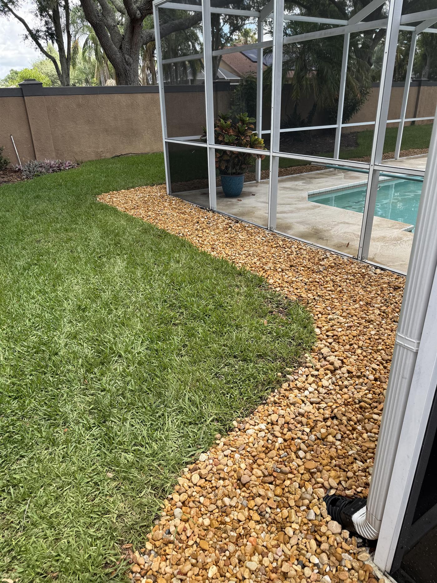 Decorative rock bed wrapping the side of a screened patio with fresh grass beside it.