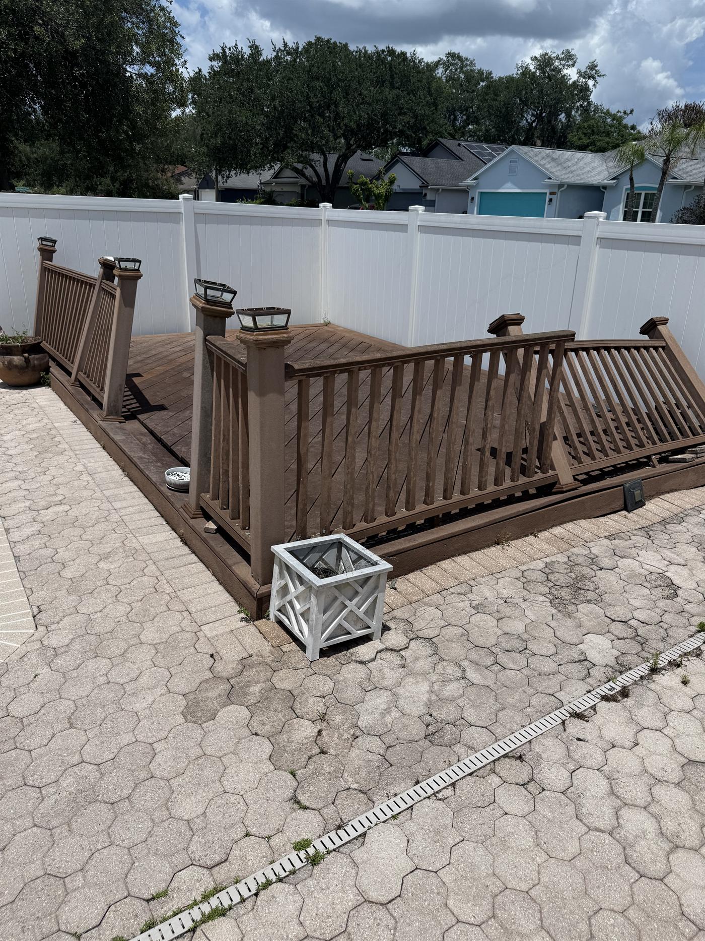Clean outdoor deck and paver area beside a backyard pool.